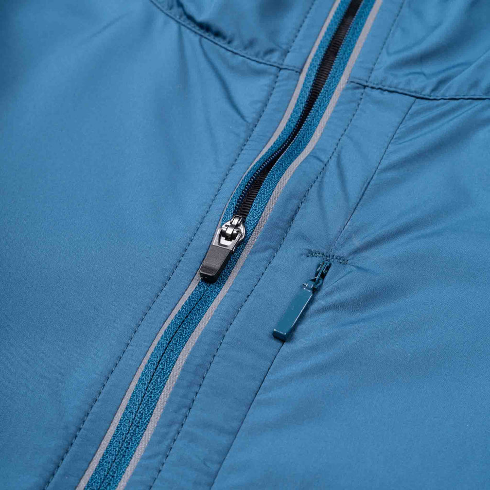 Close-up view of the front zip of the Ronhill Women's Tech Reflect Jacket in the Legion Blue/Reflect colourway.