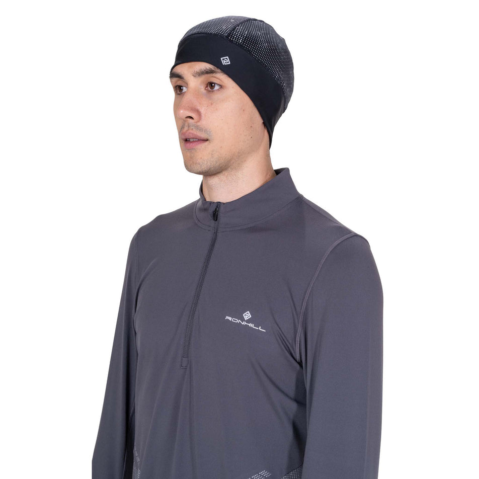 Front view of a model wearing the Ronhill Unisex Reflect Beanie in the Black/Reflect colourway.