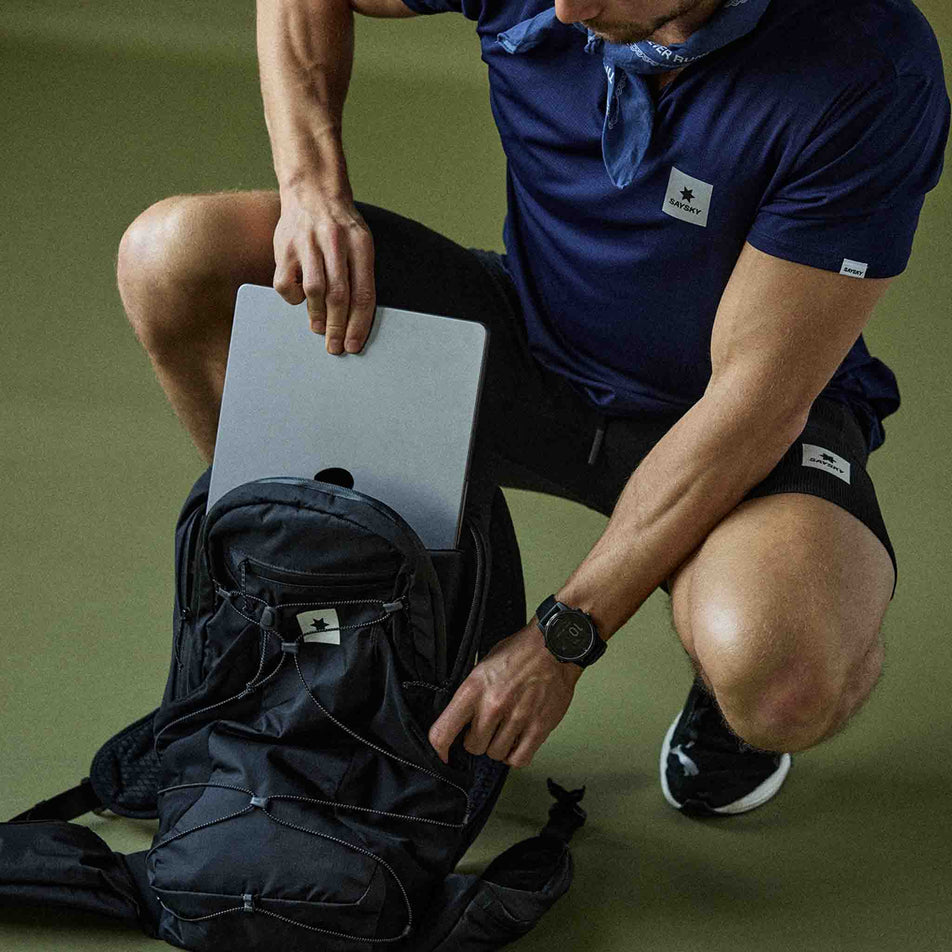 A model demonstrating the laptop storage sleeve in the SAYSKY Unisex Commuter Backpack 14L in the Black colourway.