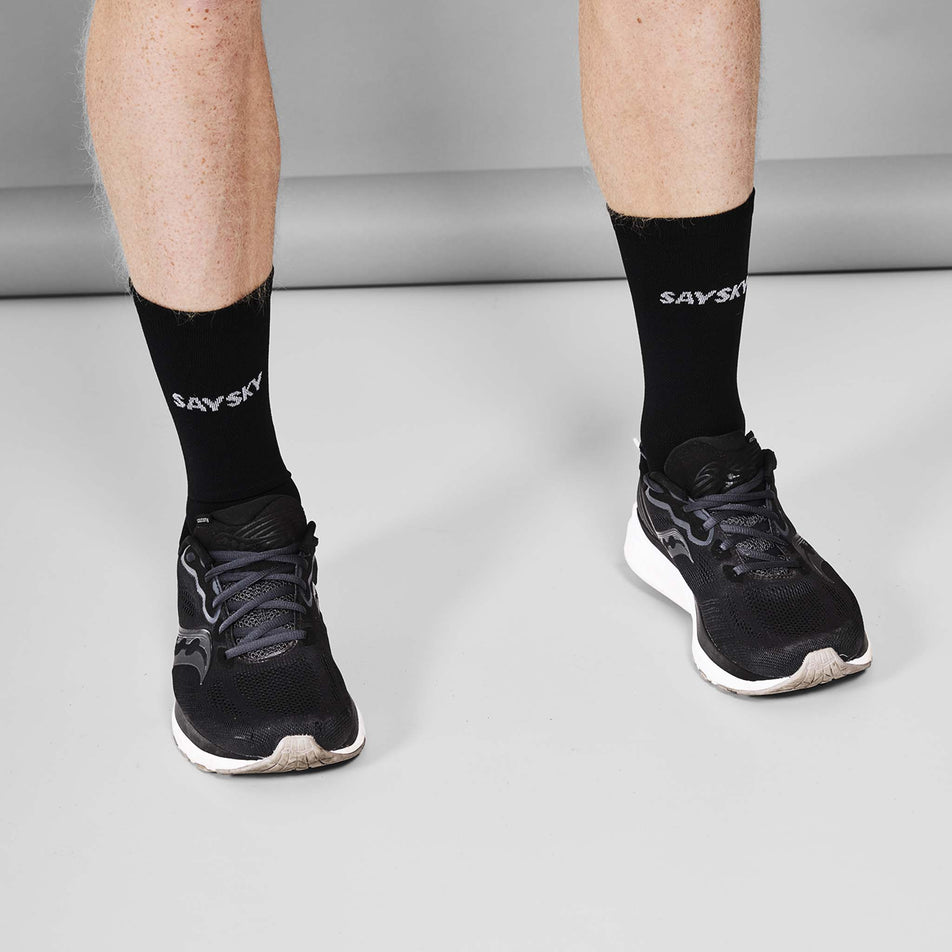 A model wearing a pair of SAYSKY Unisex Combat High Socks in the Black/White colourway. 