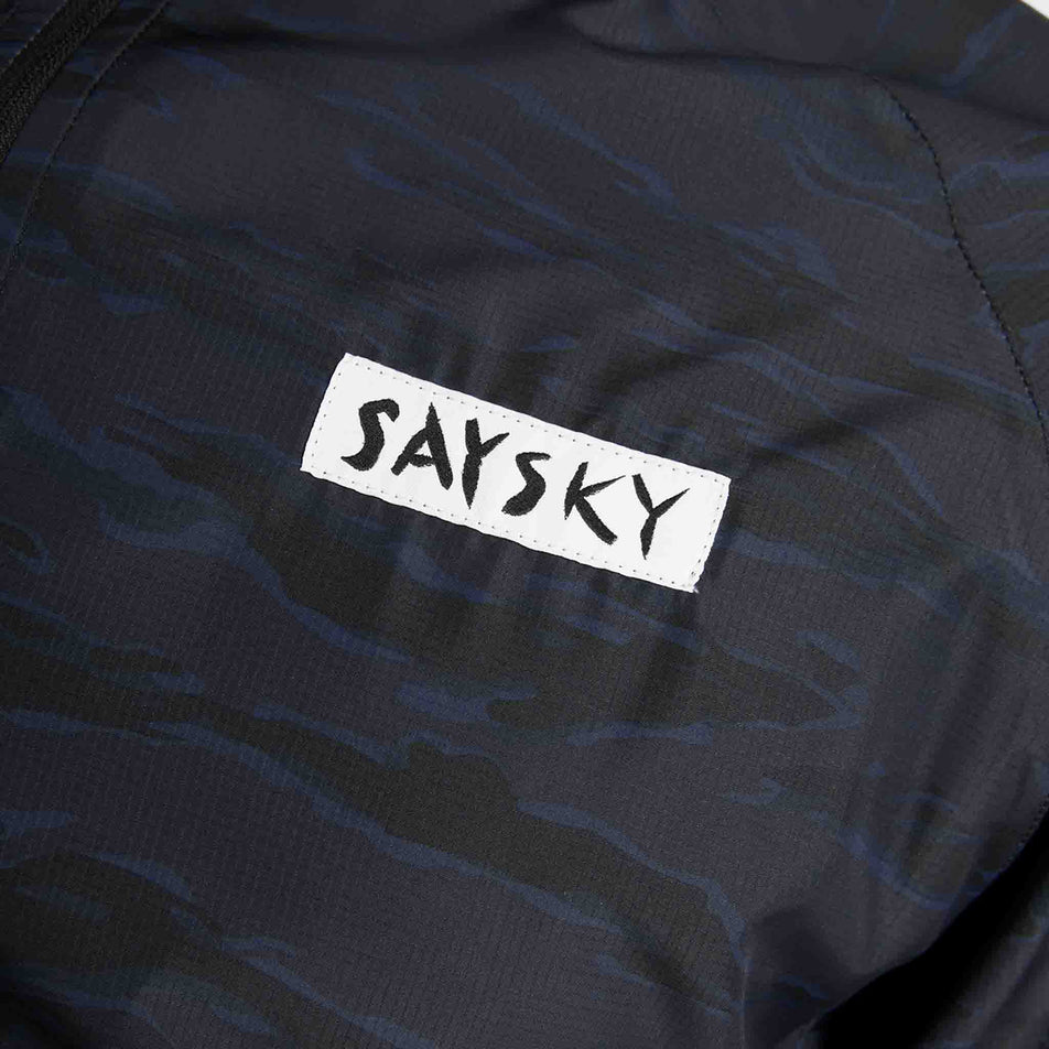 Close-up view of the SAYSKY logo on the chest of the SAYSKY Men's Tiger Pace Jacket in the Black Camo colourway.