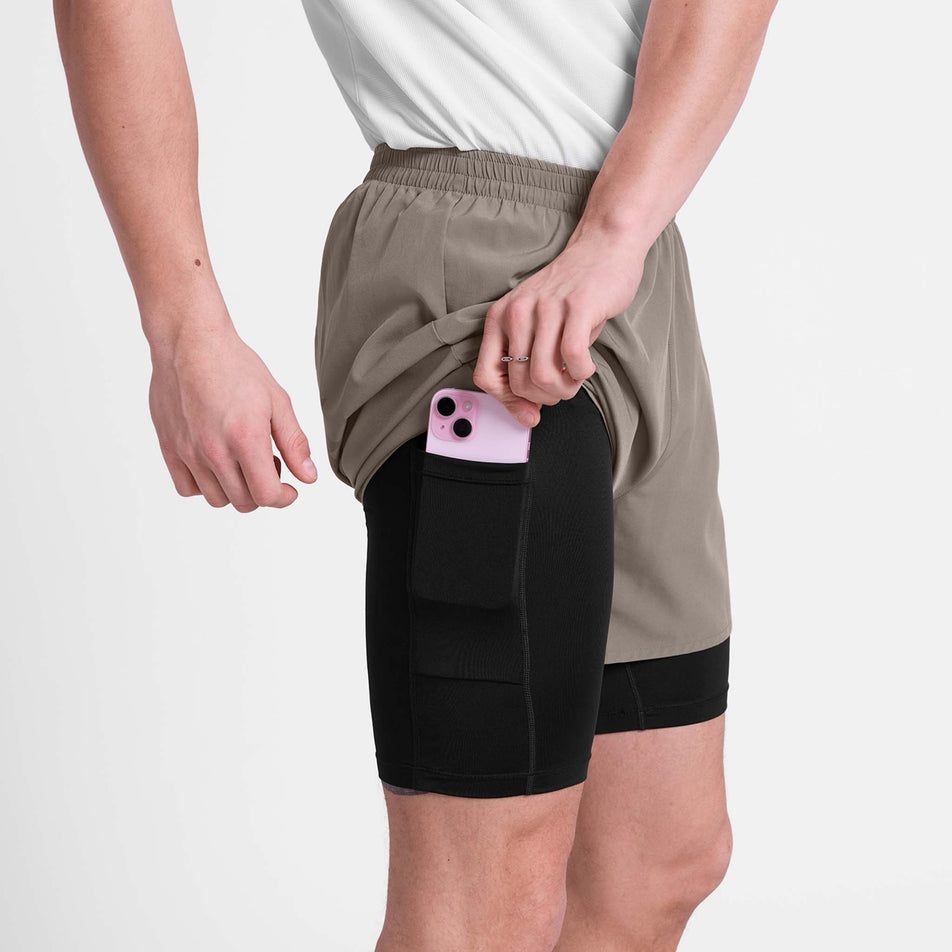 A model demonstrating the drop-in pocket on the SAYSKY Men's Pace 2 In 1 Shorts 5