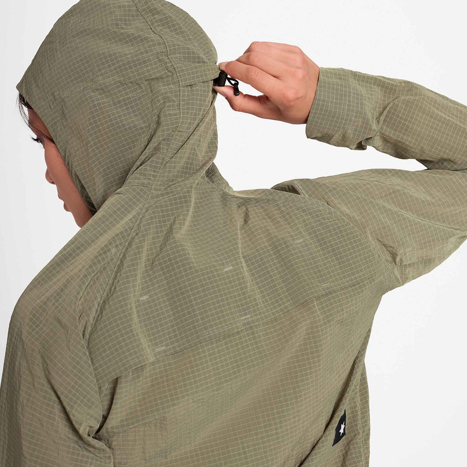 A model demonstrating the adjustable toggle on the hood of the SAYSKY Women's Clean Pace Shield Jacket in the Beige colourway.