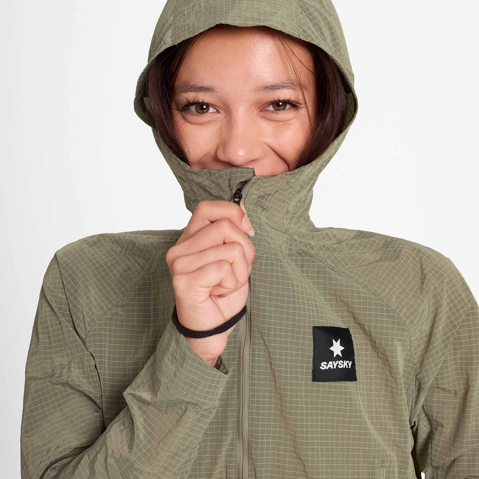 Front view of a model wearing the SAYSKY Women's Clean Pace Shield Jacket in the Beige colourway.