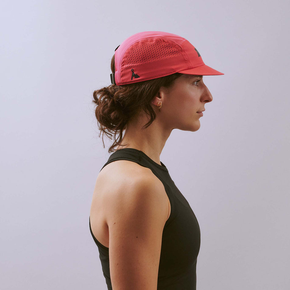 Side view of  a model wearing the VÅGA Unisex Feather Racing Cap in the Pink colourway. 