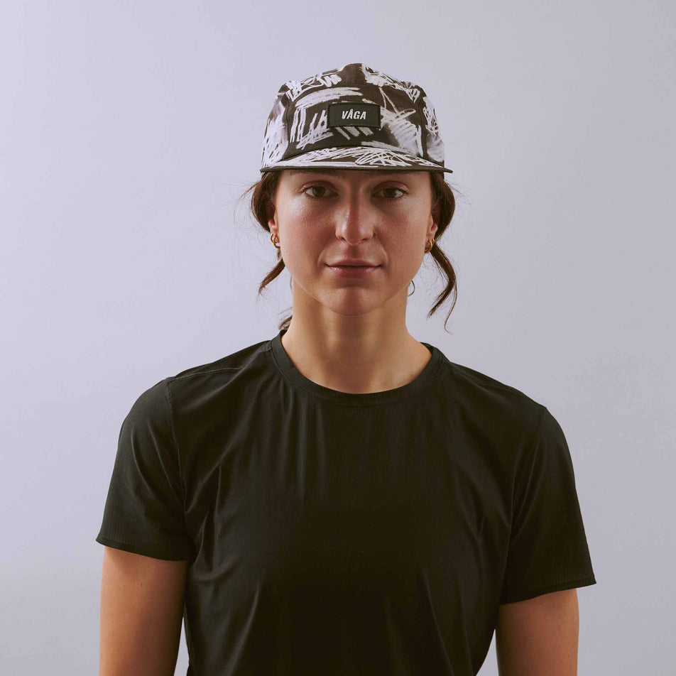 Front view of a model wearing the VÅGA Unisex Scribble Cap 2.0 in the Black/White colourway.