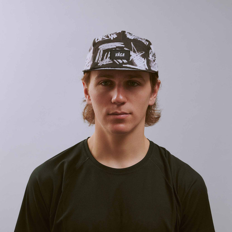 Front view of a model wearing the VÅGA Unisex Scribble Cap 2.0 in the Black/White colourway.