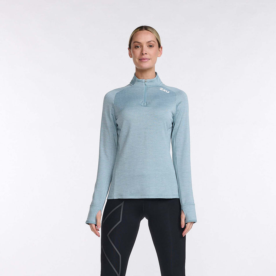 Front view of a model wearing a 2XU Women's Ignition 1/4 Zip top in the Chambray/White Reflective colourway. Model is also wearing leggings.  (8108368953506)