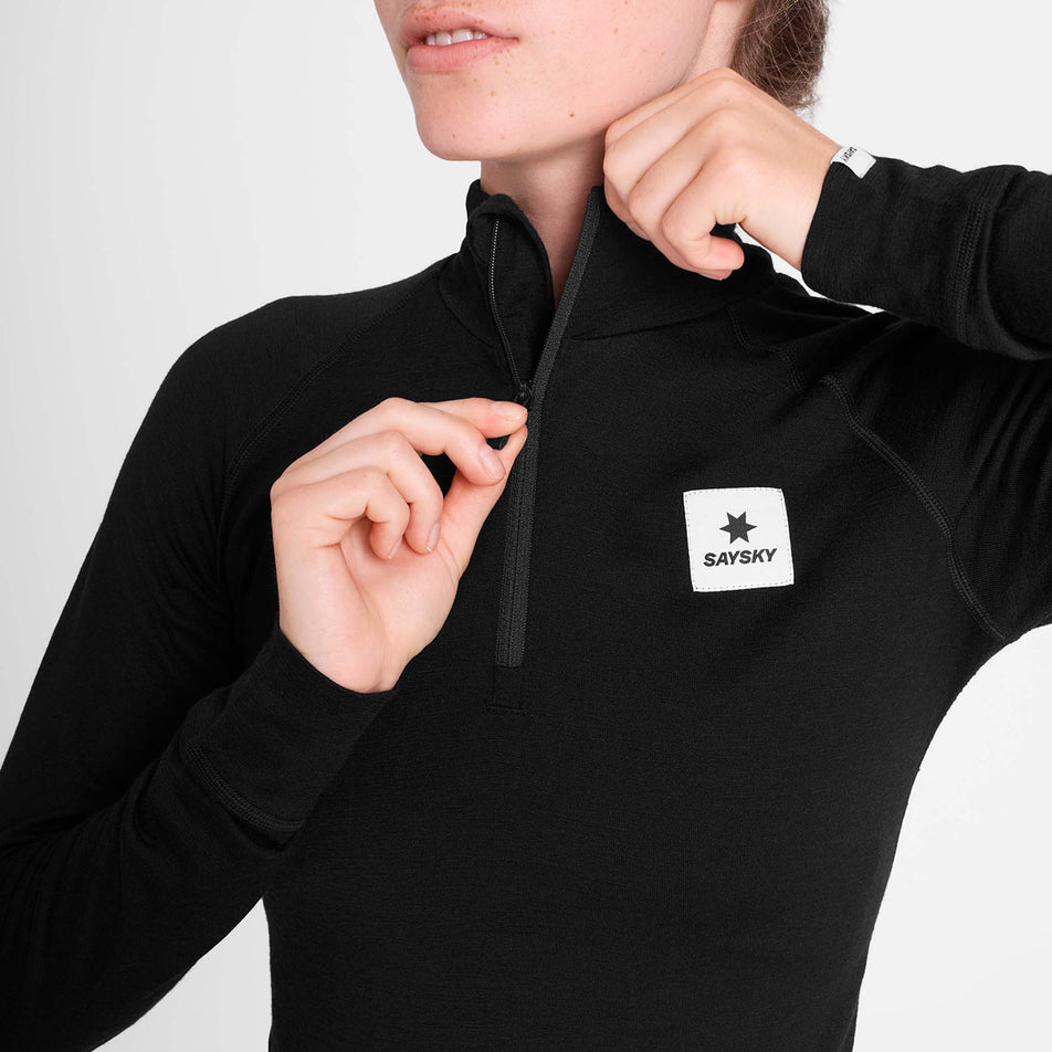 Front view of a model wearing the SAYSKY Women's Merino 165 Base 1/2 Zip Long Sleeve in the Black colourway.