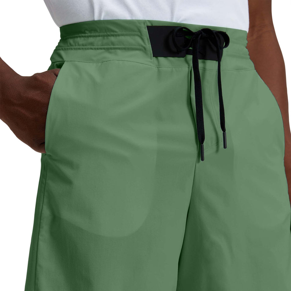 Close-up front view of a model wearing a pair of men's On Hybrid Shorts in the ivy colour (7763890536610)