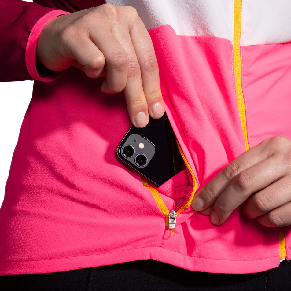 A mobile phone in a front zipped pocket on a Brooks Women's Canopy Jacket (7778531082402)