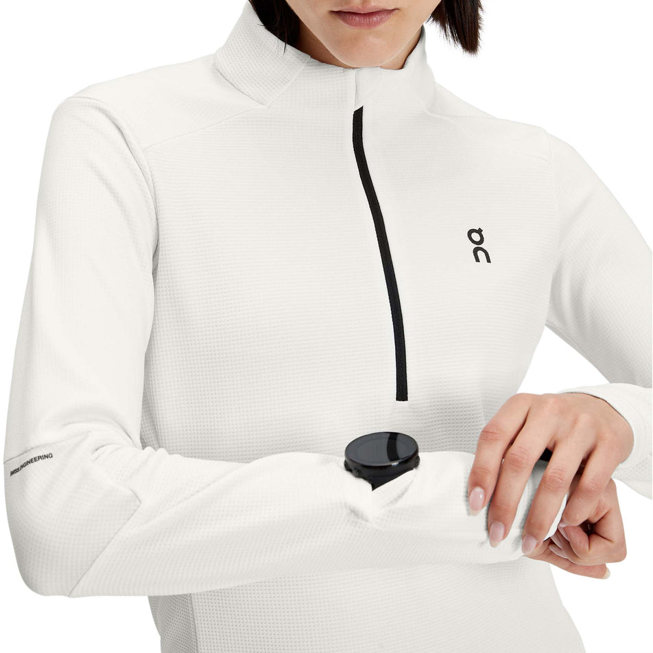 A model showing the gap for a running watch in the sleeve of a women's On Climate Shirt in the Undyed-White colour (7763913474210)