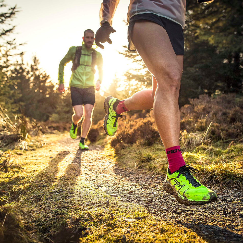 Two models wearing a pair of Inov-8 TrailFly Ultra G 300 Max each whilst running through a forest (6897229627554)
