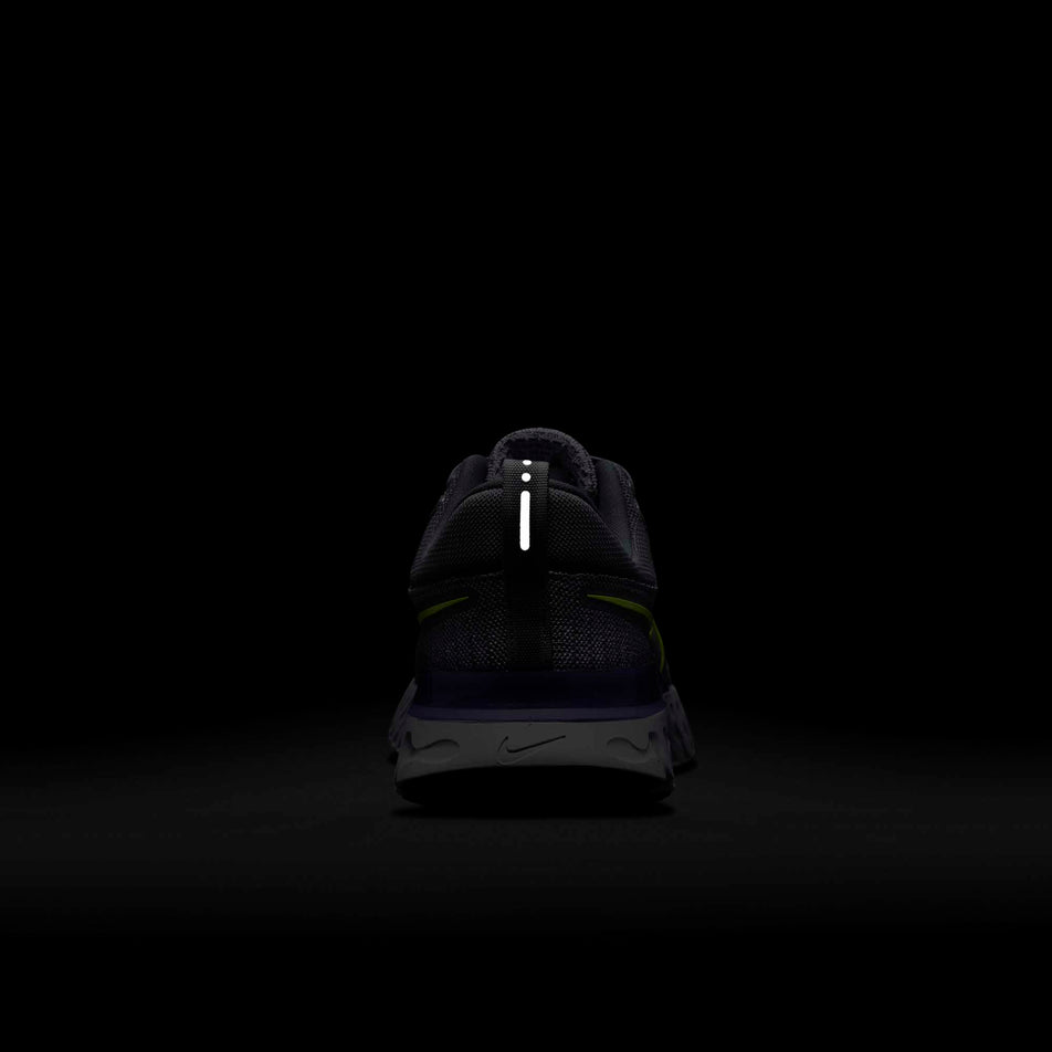 The reflective heel tab on a  Nike React Infinity Run Flyknit 2 shoe glowing in a dark surrounding  (6899658719394)