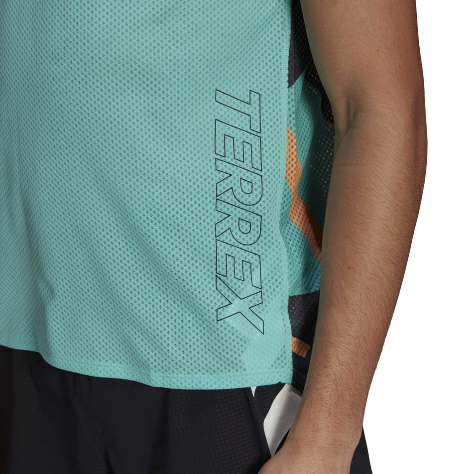 The left side of a model wearing a men's adidas TERREX AGR Singlet GFX with focus on the 'TERREX' detailing  (6929419272354)