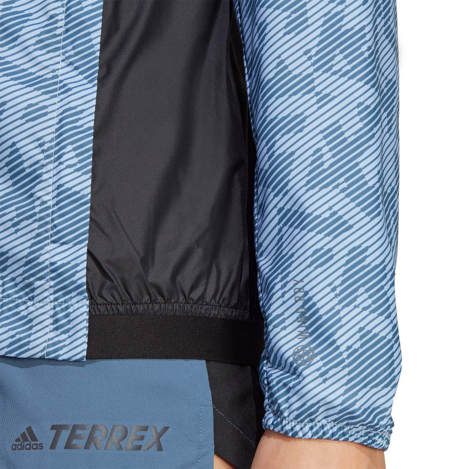 Close-up front view of a model wearing an adidas Women's Primeblue Trail Windbreaker Print - elasticated detail at side of waist section, and sleeve detail at the wrist cuff (7765651259554)