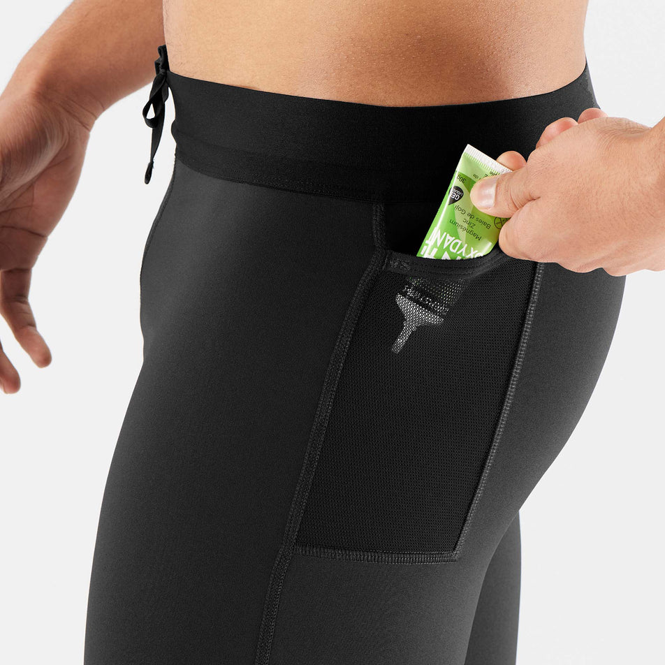 A model demonstrating that an energy gel can be stored in the mesh pocket on the left hip of a pair of Salomon Men's Cross Run Tights (7566049345698)