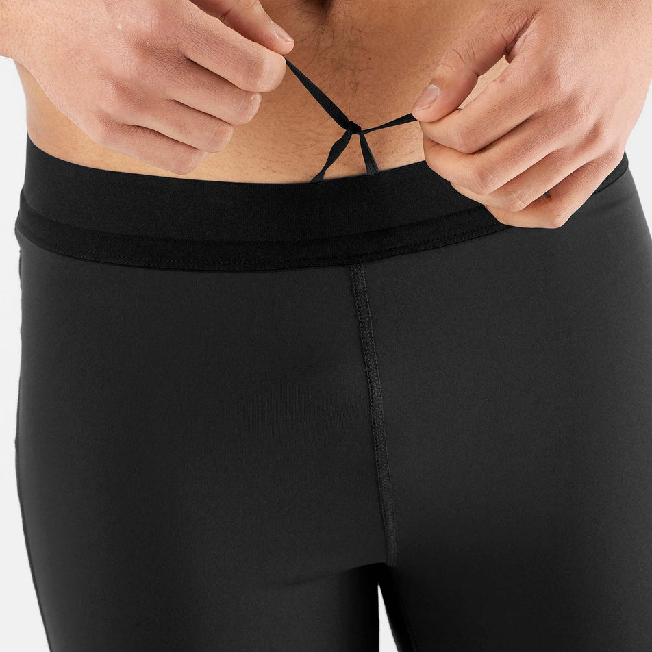 A model demonstrating the drawcord on the waistband of a pair of Salomon Men's Cross Run Tights (7566049345698)
