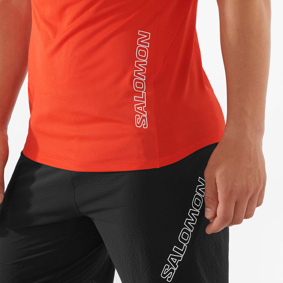 Close-up of the Salomon logo on the lower left front side of a Salomon Men's Sense Aero Short Sleeve T-Shirt in the Fiery Red colourway - being worn by a model.  (7890824069282)