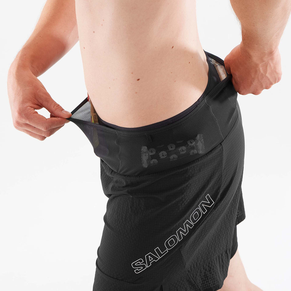 A model demonstrating the ability to store nutrition in the waistband of a pair of Salomon Men's Sense Aero 2in1 Shorts (7891202310306)