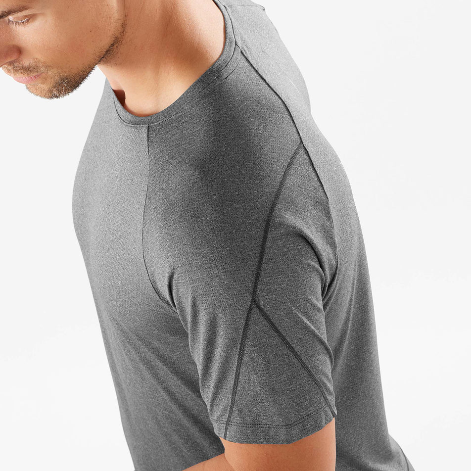 Close-up view of the stitching detail on the left shoulder of a Salomon Men's Cross Run Short Sleeve T-Shirt, in the Deep Black/Heather colour - being worn by a model (7889286824098)