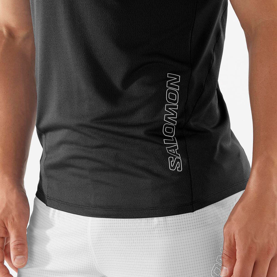 Close-up view of the Salomon logo on the lower front left section of a Salomon Men's Sense Aero Short Sleeve T-Shirt in the Deep Black colourway - being worn by a model (7890837635234)