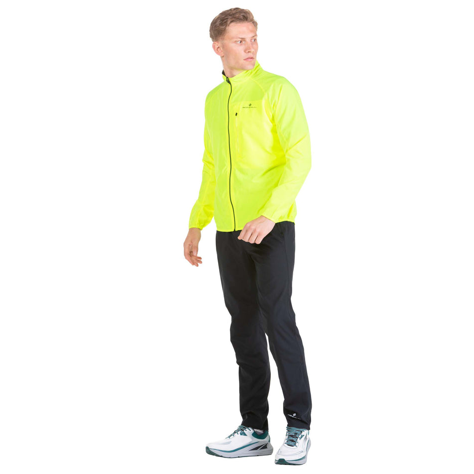 Angled front view of a model wearing a Ronhill Men's Core Jacket in the Fluo Yellow/Black colourway (6908246425762)
