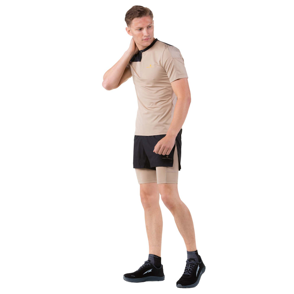 Angled front view of a model wearing a Ronhill Men's Tech Ultra 1/2 Zip Tee in the Latte/Black colourway (7744538149026)