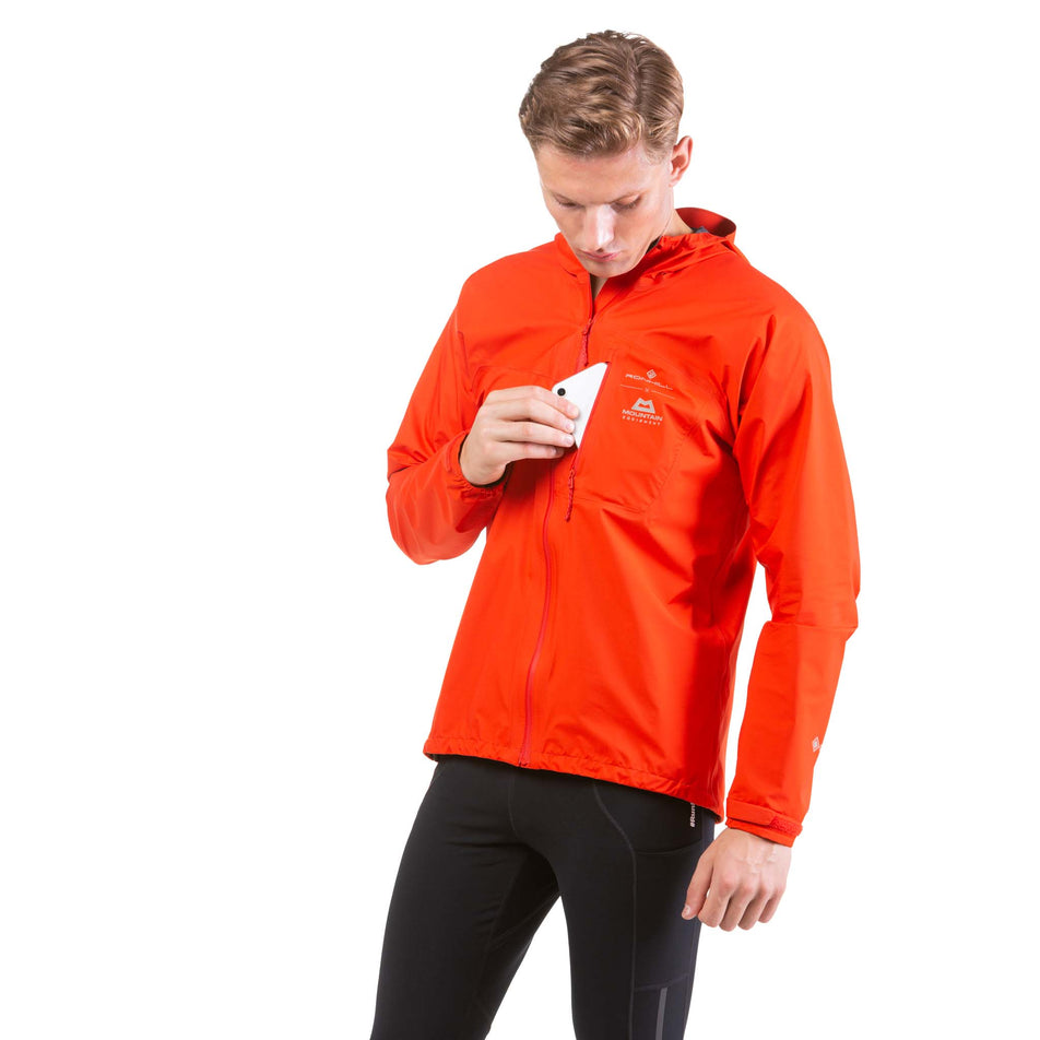 Front view of a model taking a phone out of the chest pocket on a Ronhill Men's Tech Mercurial Jacket (7743545704610)