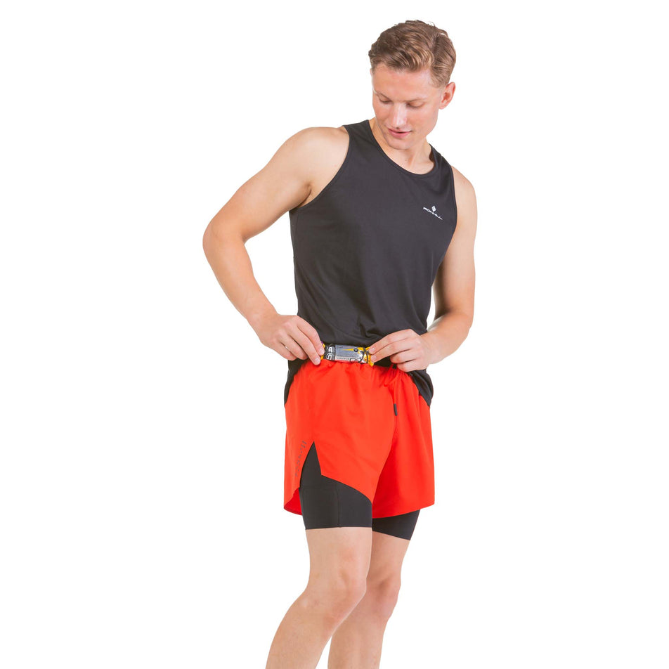 Front view of a model showing an energy gel being stored on a pair of Ronhill Men's Tech Distance Twin Shorts (7742687084706)